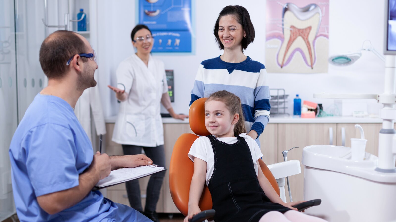 Mother and young daughter in dental operatory discussion with hygienist