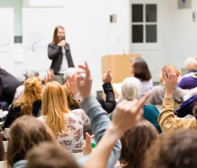 Woman speaking into microphone at a town hall meeting